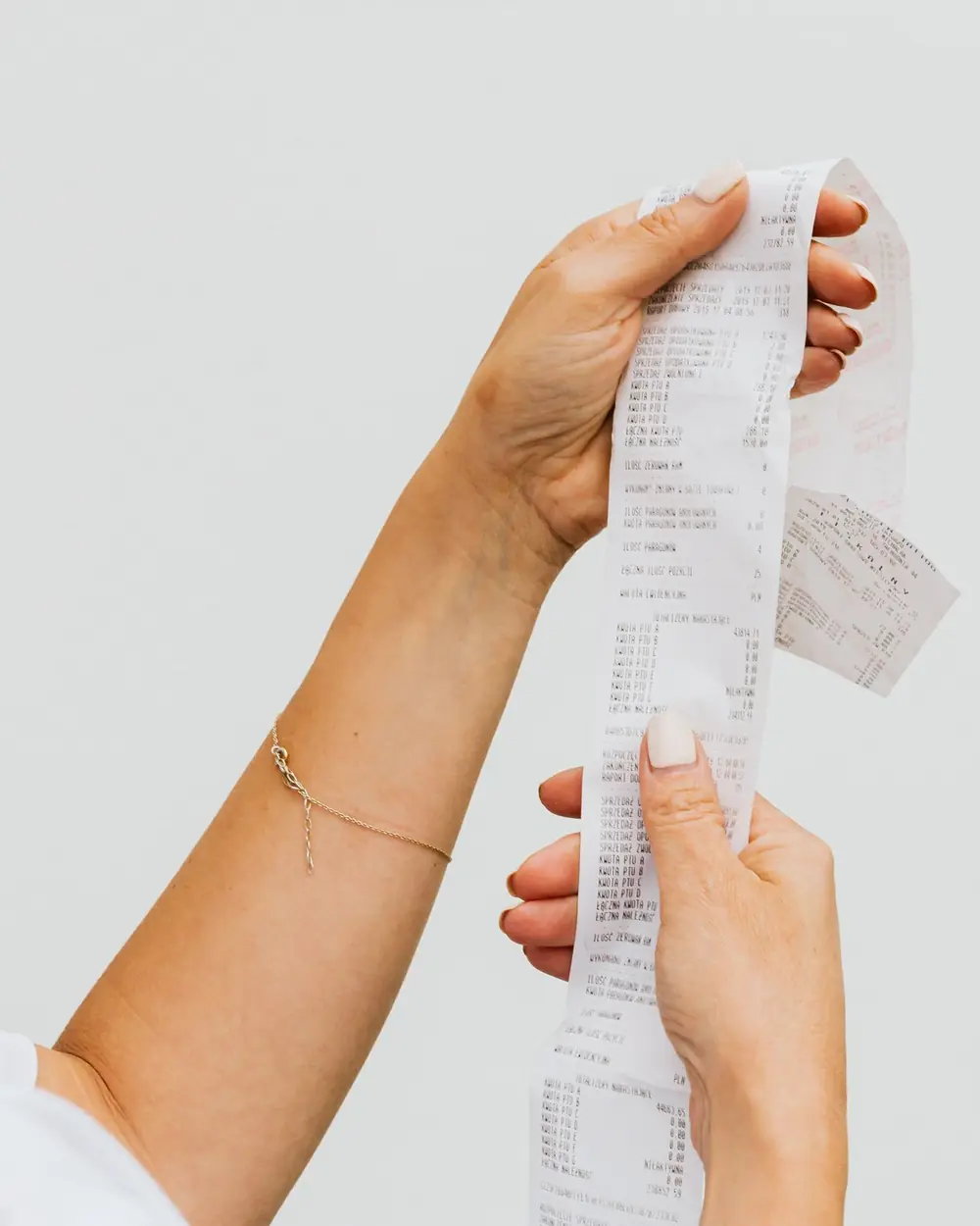 Two hands holding a long printed till receipt.